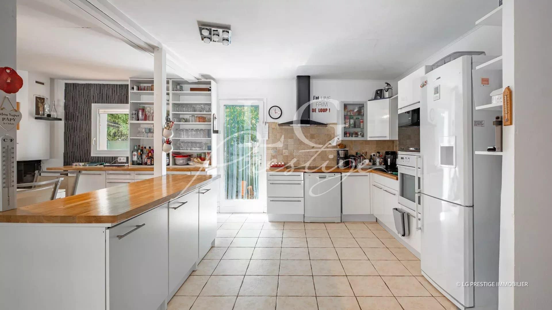 Cuisine moderne et lumineuse d'une villa de plain-pied à Fayence, avec meubles blancs et plan de travail en bois.