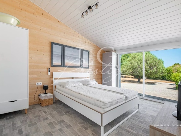 Chambre d'une villa moderne avec lit double et accès à l'extérieur.