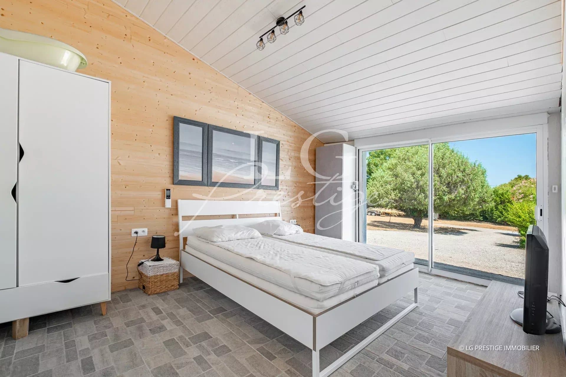 Chambre d'une villa moderne avec lit double et accès à l'extérieur.