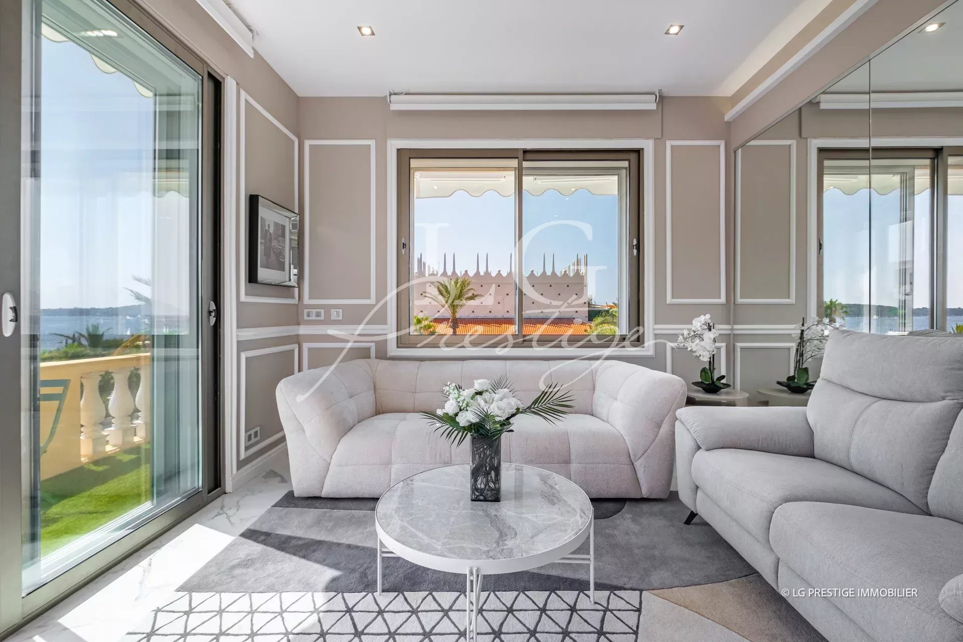 Salon lumineux d'un appartement rénové à Cannes, avec vue sur la mer et accès à une terrasse.