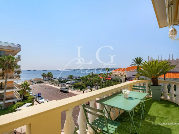 Vue depuis une terrasse avec table et chaises, sur la mer et le quartier de Palm Beach à Cannes.