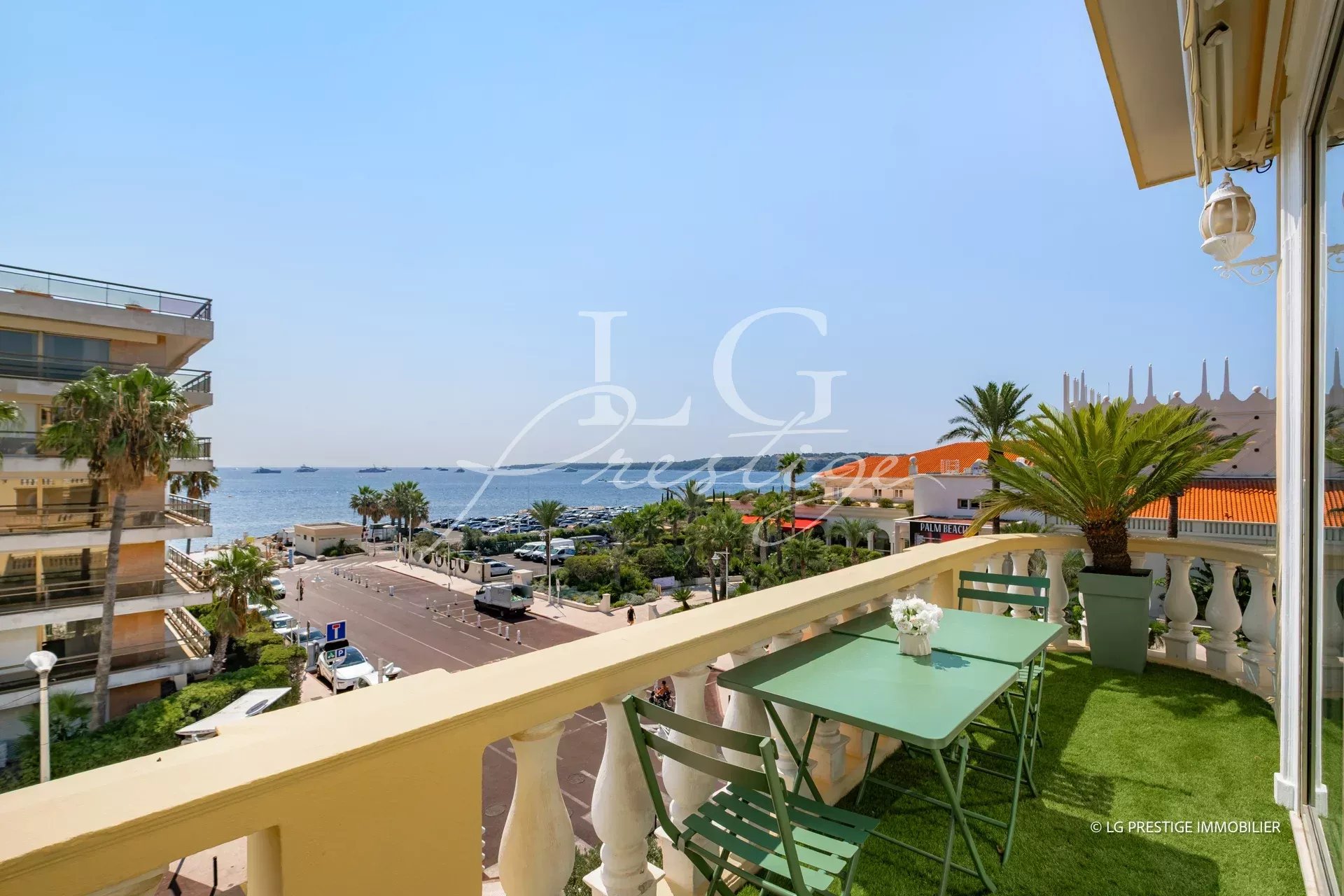 Vue depuis une terrasse avec table et chaises, sur la mer et le quartier de Palm Beach à Cannes.