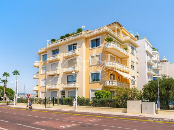 Immeuble résidentiel sur la Pointe Croisette à Cannes, avec palmier et route en premier plan.