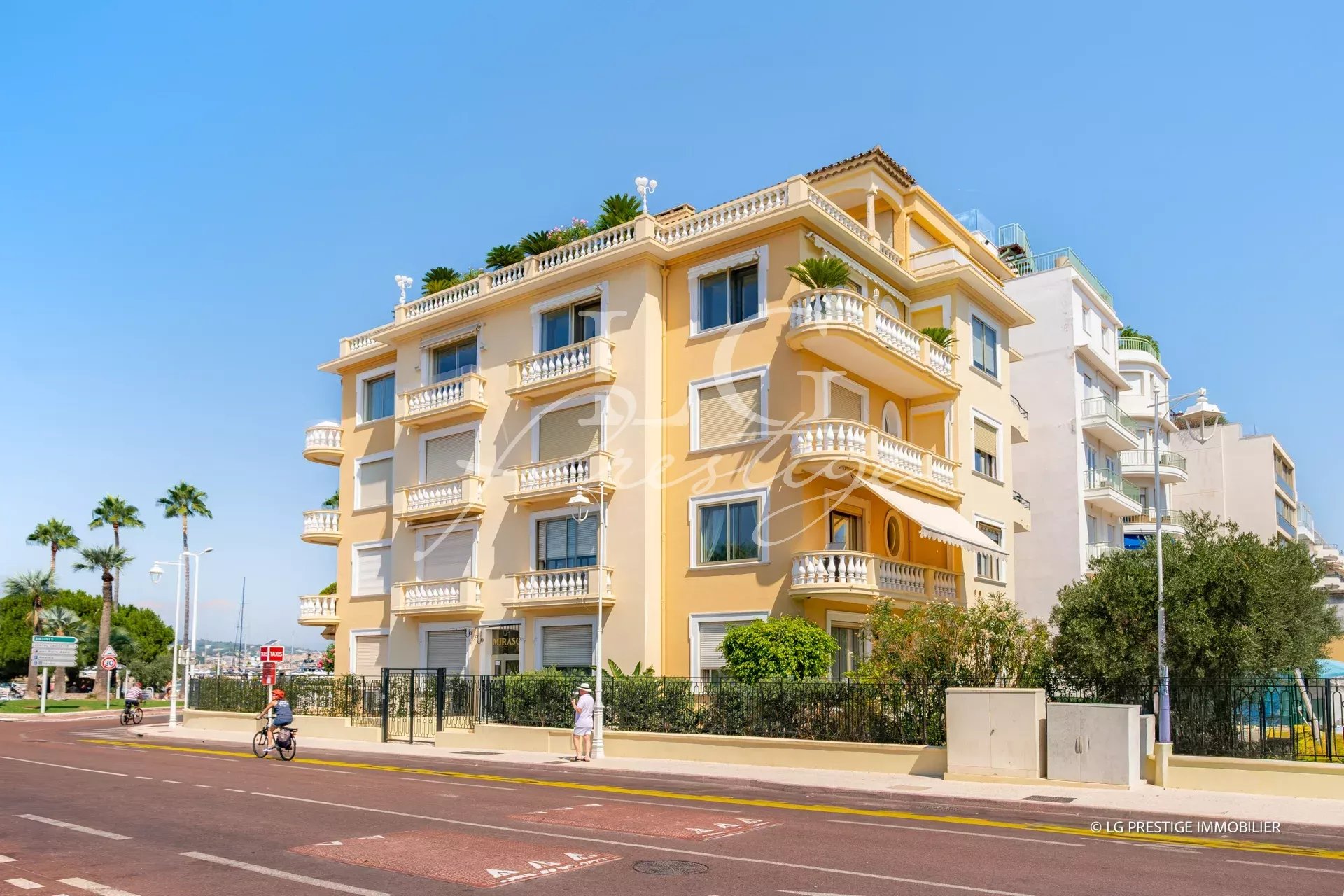 Immeuble résidentiel sur la Pointe Croisette à Cannes, avec palmier et route en premier plan.