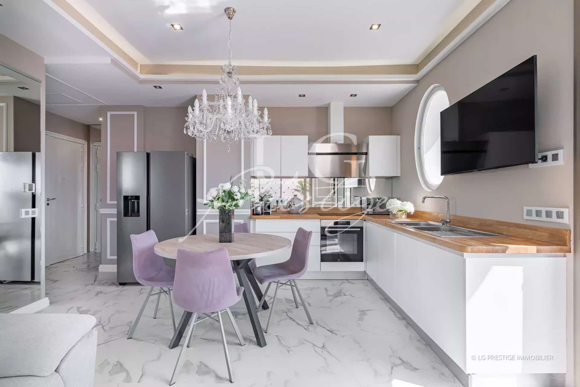 Cuisine moderne et lumineuse avec salle à manger dans un appartement rénové à Cannes.