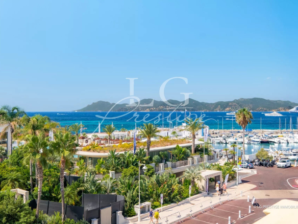 Vue de la mer depuis la Pointe Croisette à Cannes, avec des yachts au port et des palmiers.
