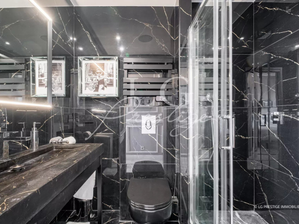 Salle de bain moderne avec douche, toilettes et lavabo en marbre noir.