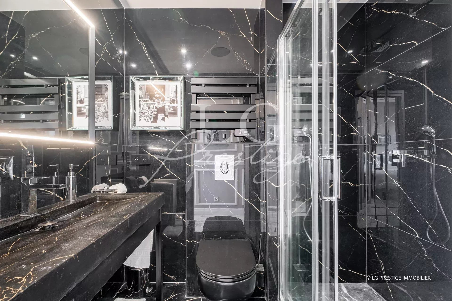 Salle de bain moderne avec douche, toilettes et lavabo en marbre noir.