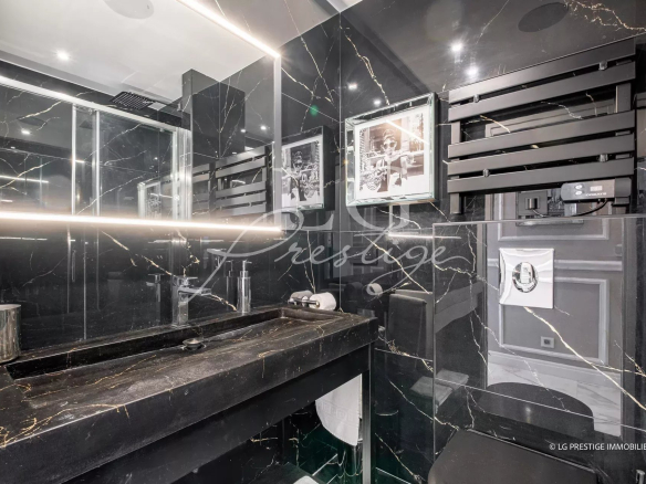 Salle de bain moderne avec murs en marbre noir et éclairage LED.