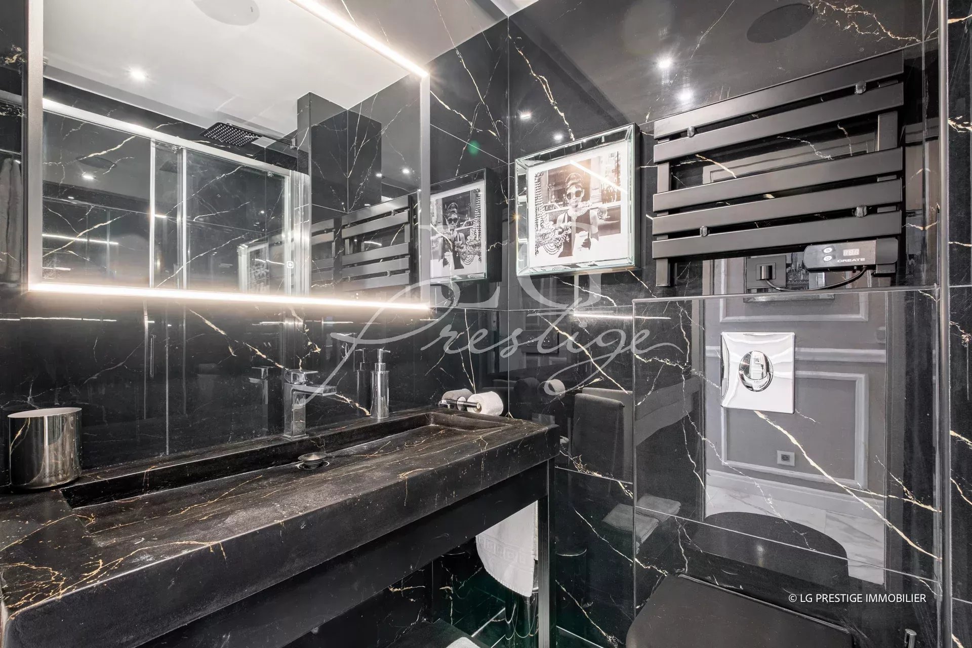 Salle de bain moderne avec murs en marbre noir et éclairage LED.