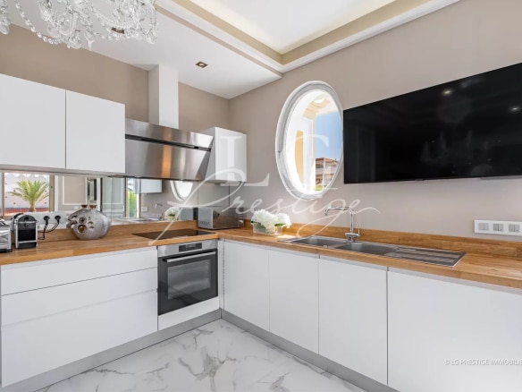 Cuisine moderne avec plans de travail en bois et appareils électroménagers intégrés.
