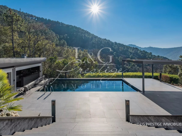 Vue de la piscine et des terrasses d'une villa contemporaine à Mandelieu-La-Napoule, entourée de nature.