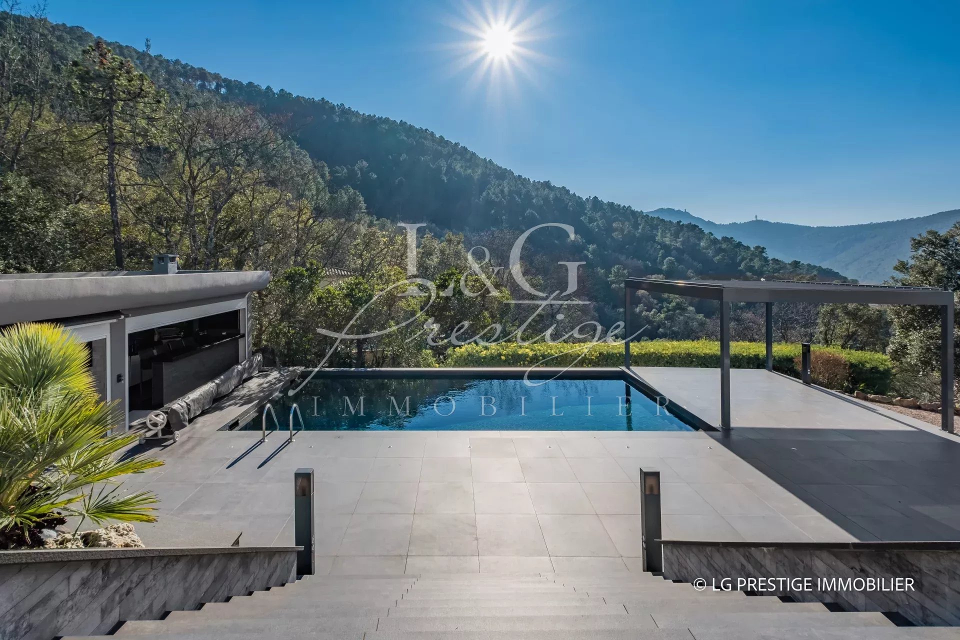 Vue de la piscine et des terrasses d'une villa contemporaine à Mandelieu-La-Napoule, entourée de nature.