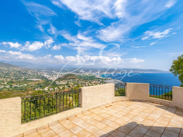 Panoramic sea view from a terrace in Théoule-sur-Mer, with blue sky and green landscape.