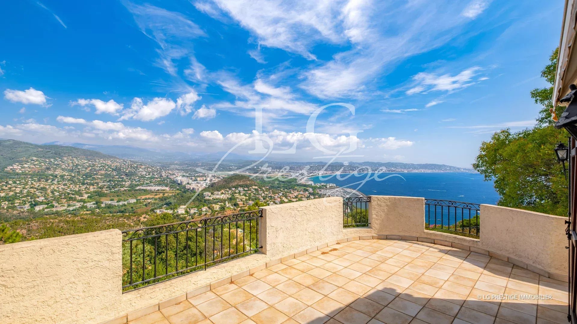 Panoramic sea view from a terrace in Théoule-sur-Mer, with blue sky and green landscape.