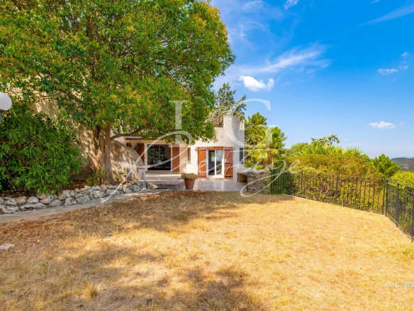 View of a villa with garden and trees in Théoule-sur-Mer, blue sky and clouds.