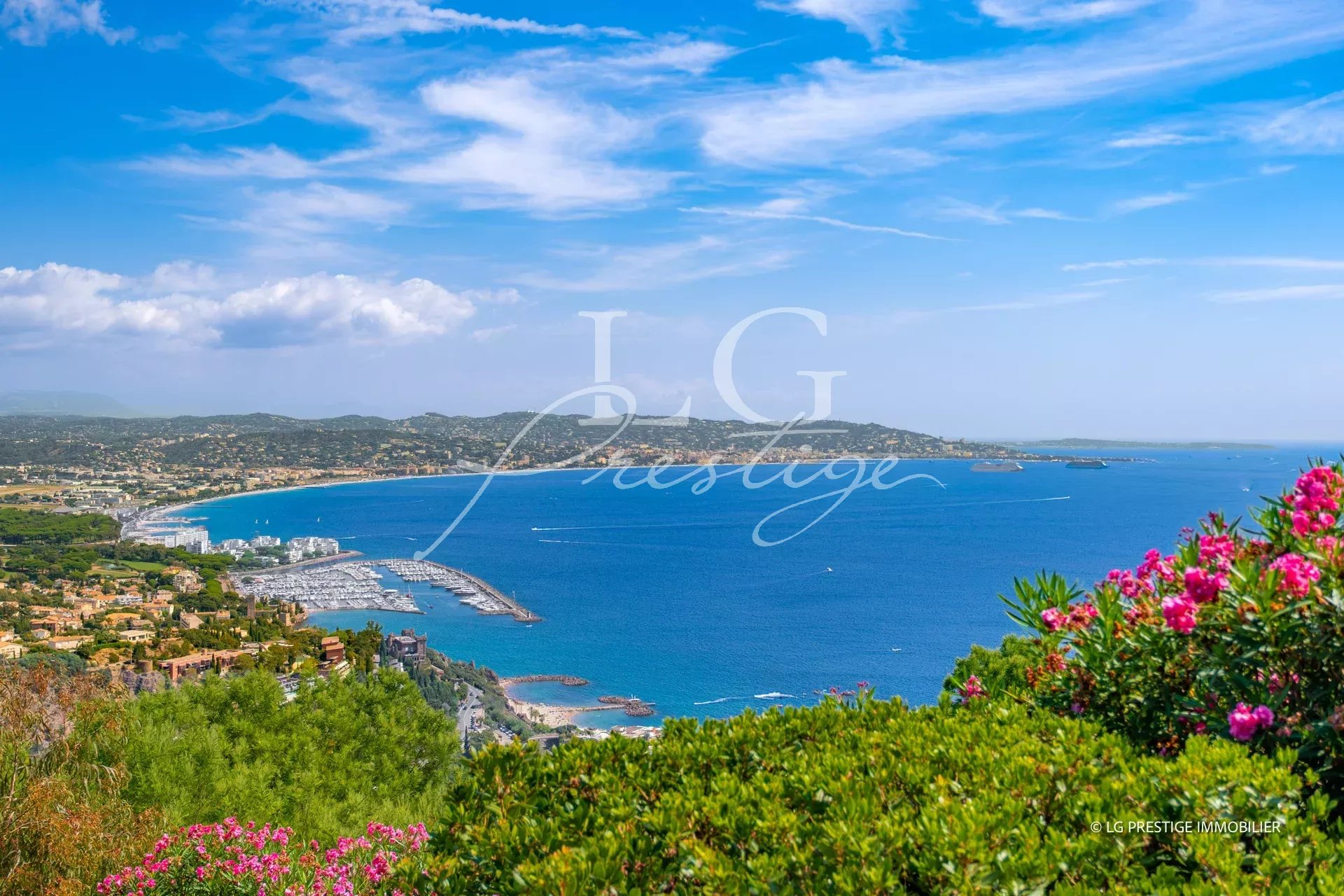 Panoramic sea view from Théoule-sur-Mer, with hills and flowers in the foreground.