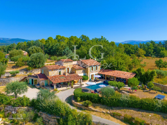 Stone property with swimming pool and outbuilding in Montauroux, surrounded by greenery.