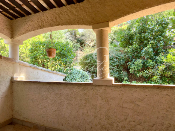 Terrasse avec vue sur un jardin verdoyant, murs en pierre et colonnes en pierre.