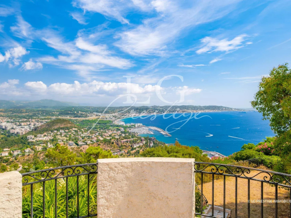 Vue panoramique sur la mer depuis une propriété à Théoule-sur-Mer, avec ciel bleu et collines en arrière-plan.