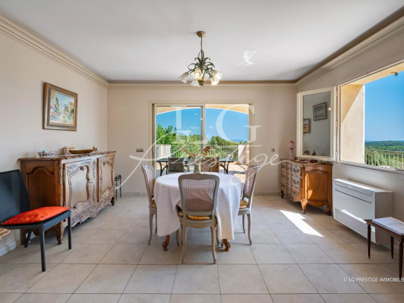 Intérieur d'une villa provençale avec salle à manger lumineuse et vue sur la nature.