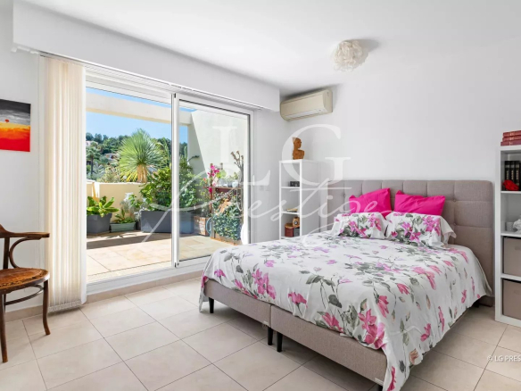 Room in an apartment in Mandelieu-la-Napoule with bed, balcony and floral decoration.