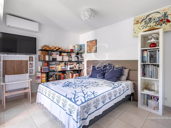 Room in a modern apartment with bed, bookcase and television.