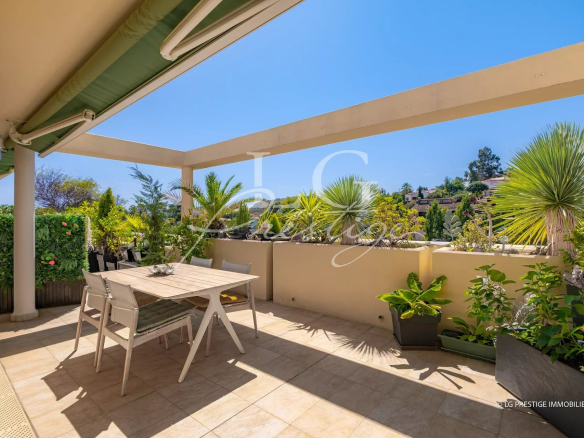 Terrace of an apartment with table and plants, sunny, in Mandelieu-la-Napoule.