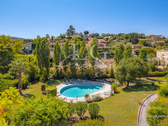 View of a swimming pool surrounded by greenery in a residence in Mandelieu-la-Napoule.