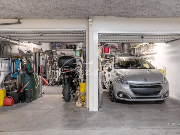 Garage with two parking spaces, one for a car and one for a motorcycle, surrounded by tools and equipment.