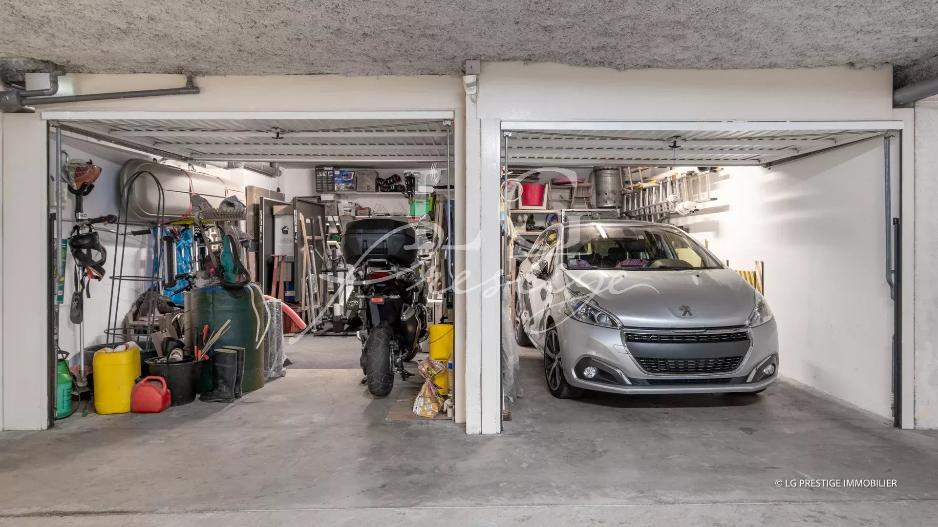 Spacious garage in Mandelieu-la-Napoule Garage with two parking spaces, one for a car and one for a motorcycle, surrounded by tools and equipment.