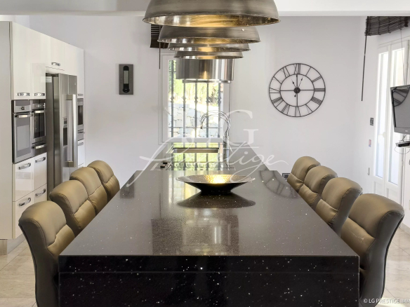 Cuisine moderne avec une grande table en marbre et des chaises confortables.