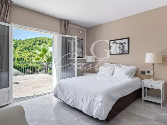 Chambre d'une demeure à Grasse avec accès à une terrasse et vue sur la verdure.