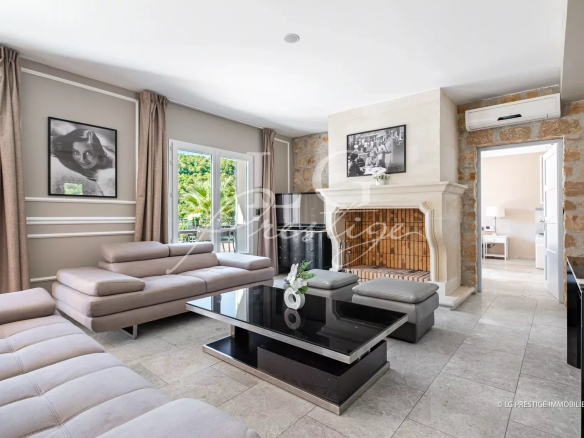 Intérieur d'une maison à Grasse avec un salon moderne, cheminée et grandes fenêtres.