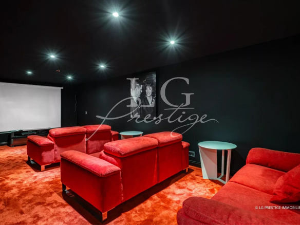 Salle de cinéma avec canapés rouges et écran de projection dans une propriété à Grasse.