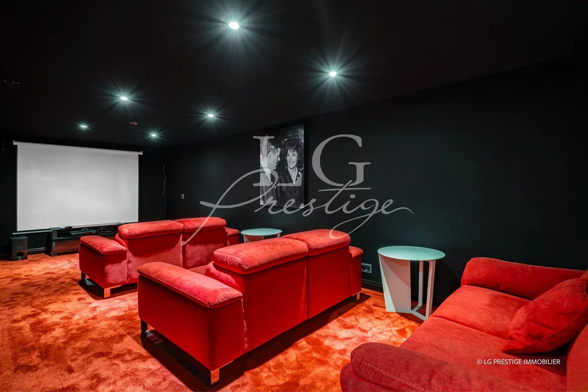 Salle de cinéma avec canapés rouges et écran de projection dans une propriété à Grasse.