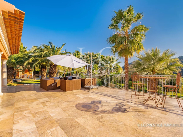 Terrasse ensoleillée avec mobilier de jardin et palmiers, vue sur la verdure à Grasse.