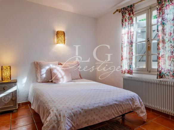 Room in a Provençal villa with a double bed, decorated with floral curtains and soft lighting.