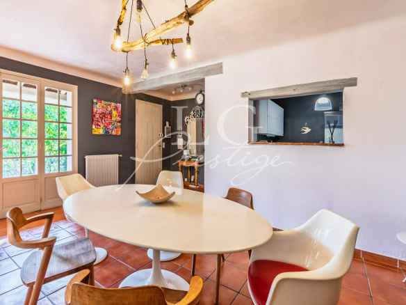 Interior of a Provençal villa with a round table and modern chairs, bathed in light.