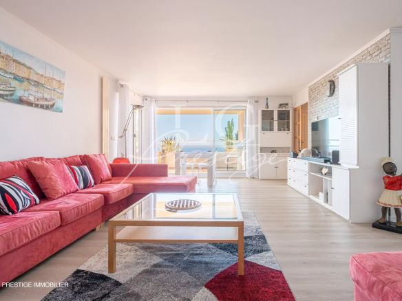 Bright living room of an apartment with a red sofa and a sea view in Mandelieu-la-Napoule.
