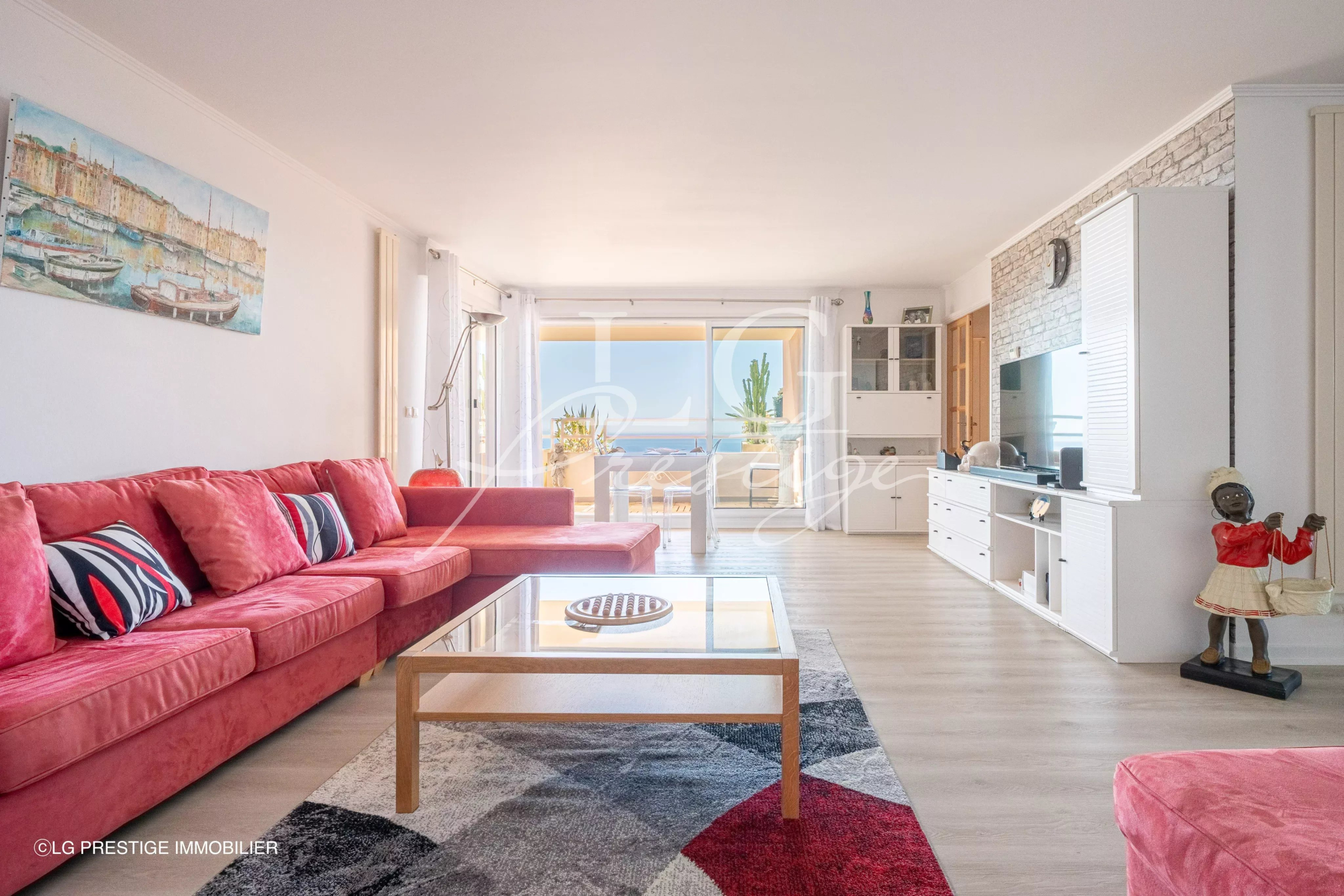 Living room of an apartment with sea view Bright living room of an apartment with a red sofa and a sea view in Mandelieu-la-Napoule.
