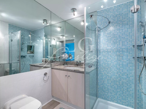 Modern bathroom with glass shower and blue tiles.