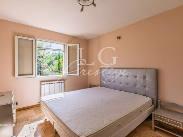 Chambre d'une bastide provençale avec lit et fenêtre donnant sur le jardin.