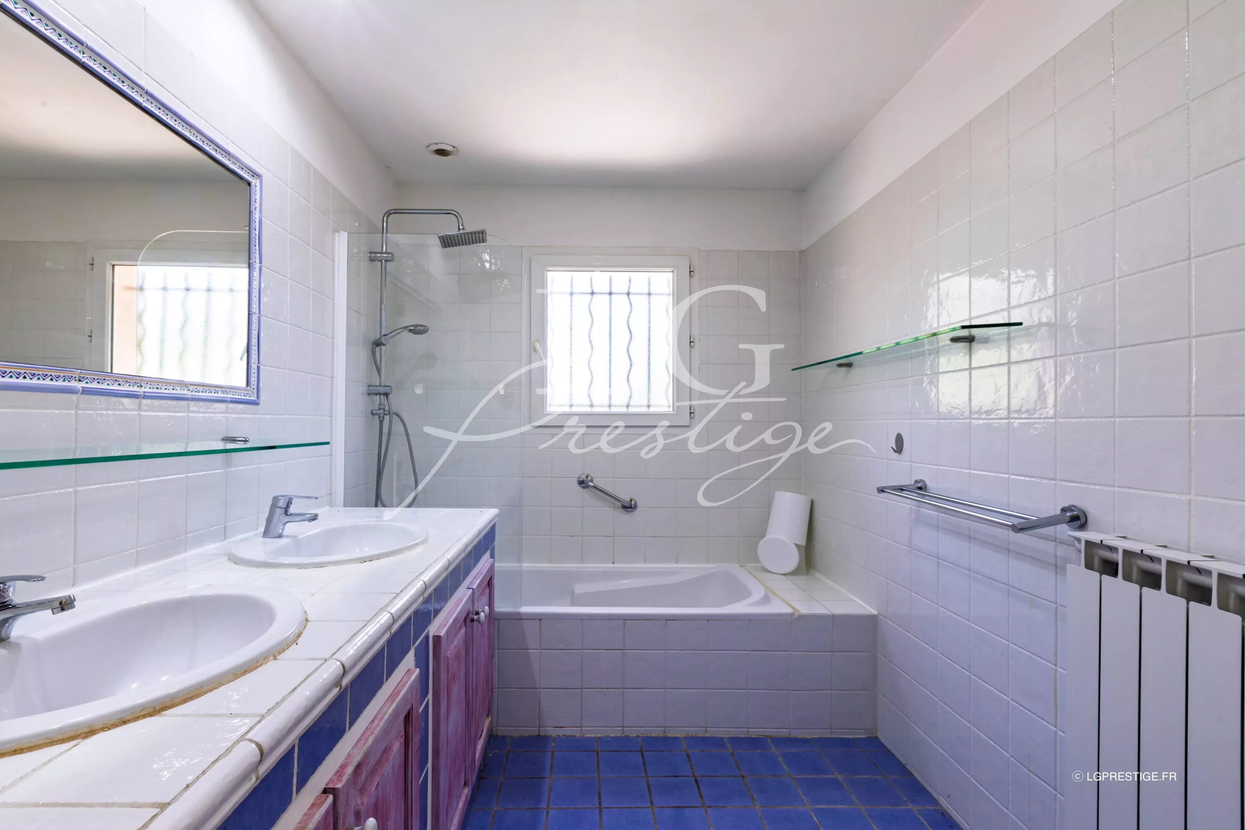 Salle de bain de la bastide provençale Salle de bain avec baignoire et douche, carrelage blanc et bleu, éclairage naturel.