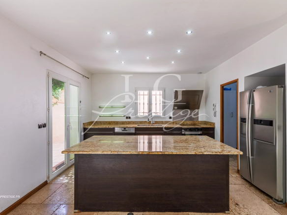 Cuisine moderne avec îlot central en granit et appareils électroménagers en inox.