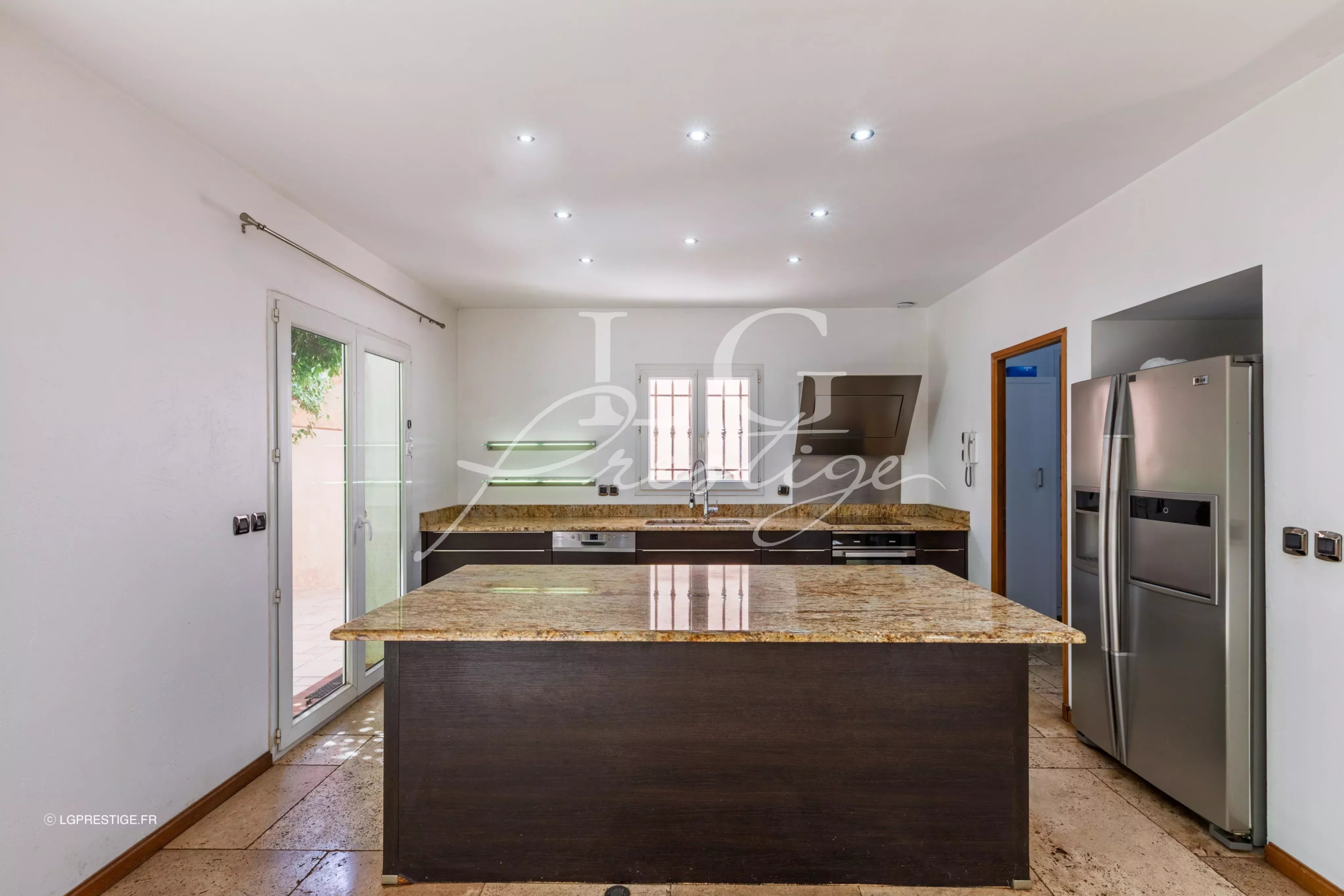 Cuisine d’une bastide provençale à Fayence Cuisine moderne avec îlot central en granit et appareils électroménagers en inox.