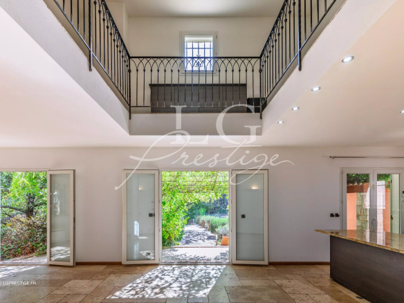 Intérieur d'une bastide provençale avec un espace ouvert et des portes vitrées donnant sur le jardin.