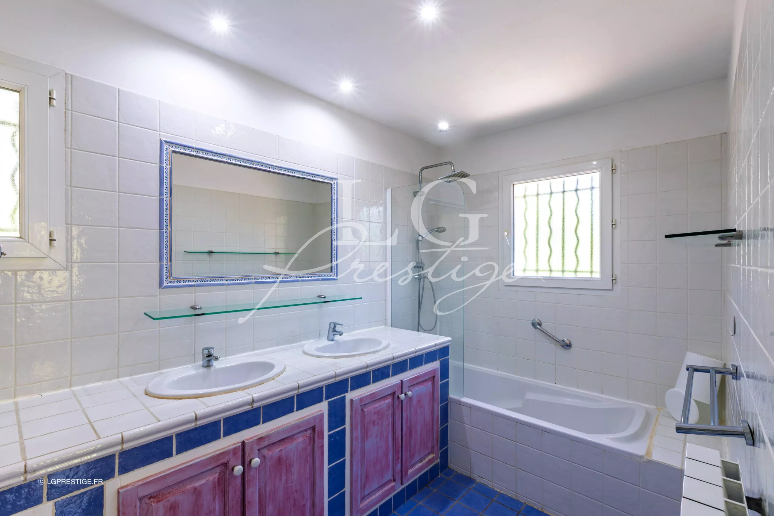 Salle de bain élégante Salle de bain avec baignoire et double vasque, carrelage blanc et bleu, lumière naturelle