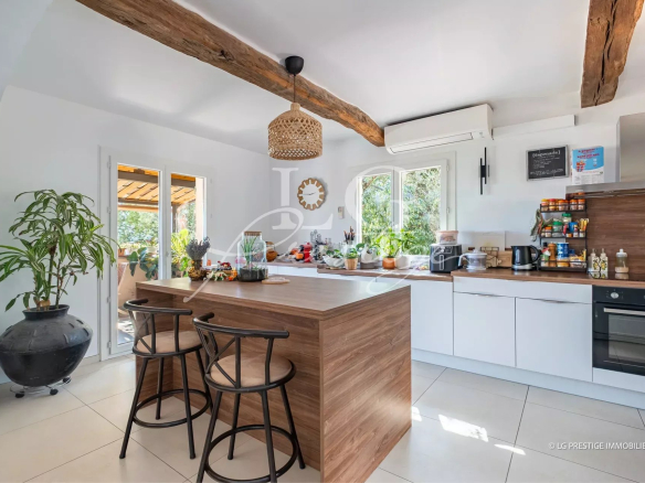 Modern kitchen with central island and bar, open to the outside, in a villa in Spéracèdes.