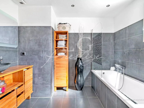 Salle de bain moderne avec baignoire et douche, décorée de carrelage gris.